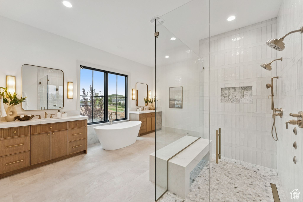 Bathroom featuring a stall shower, two vanities, a freestanding bath, and recessed lighting