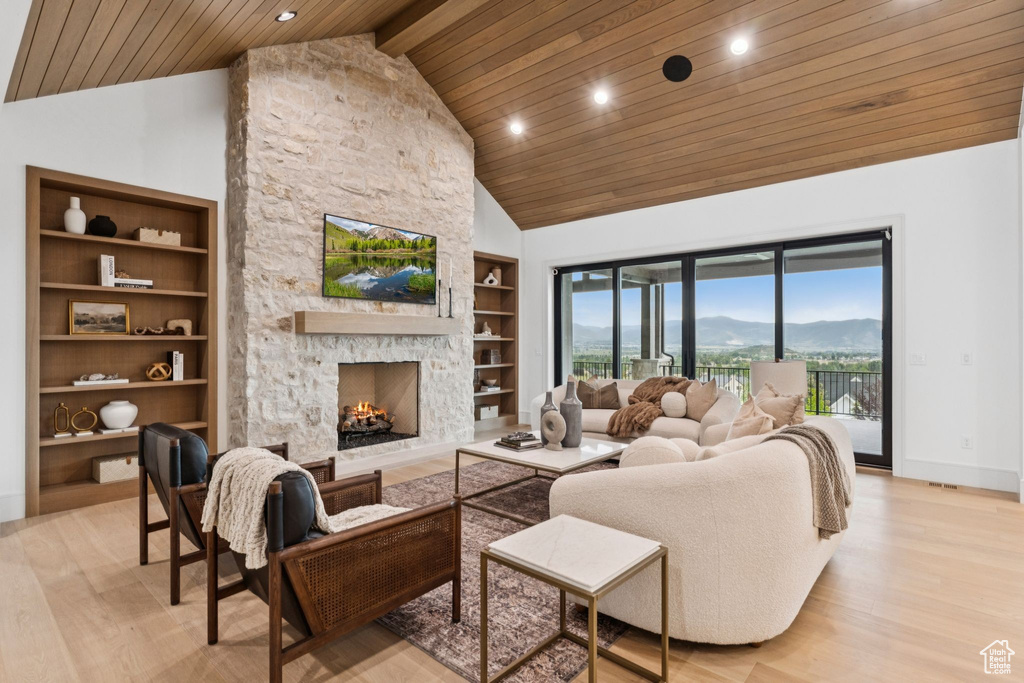 Living area with a wooden ceiling with exposed beams, light wood finished floors, recessed lighting, a fireplace, and built in shelves