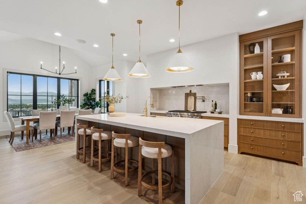 Kitchen with recessed lighting, light wood finished floors, light countertops, a breakfast bar, and a spacious island