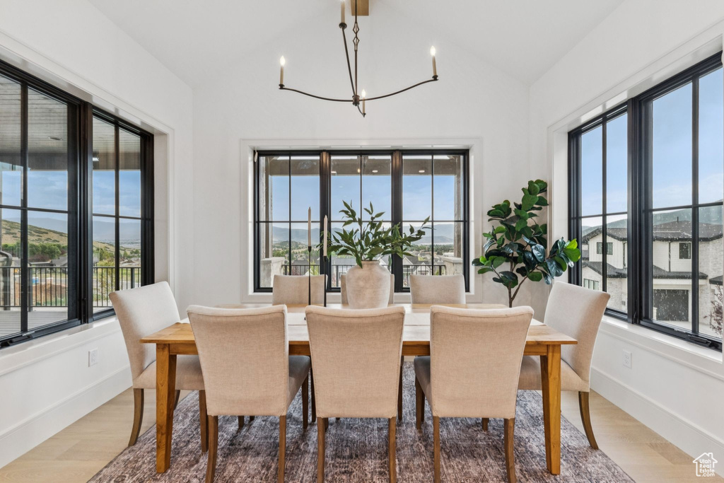 Dining area featuring lofted ceiling, a chandelier, and light wood-style flooring