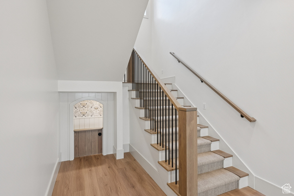 Stairs featuring wood finished floors and a high ceiling