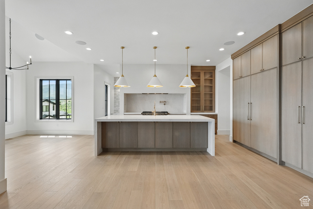 Kitchen with light wood-type flooring, light countertops, recessed lighting, baseboards, and a sink