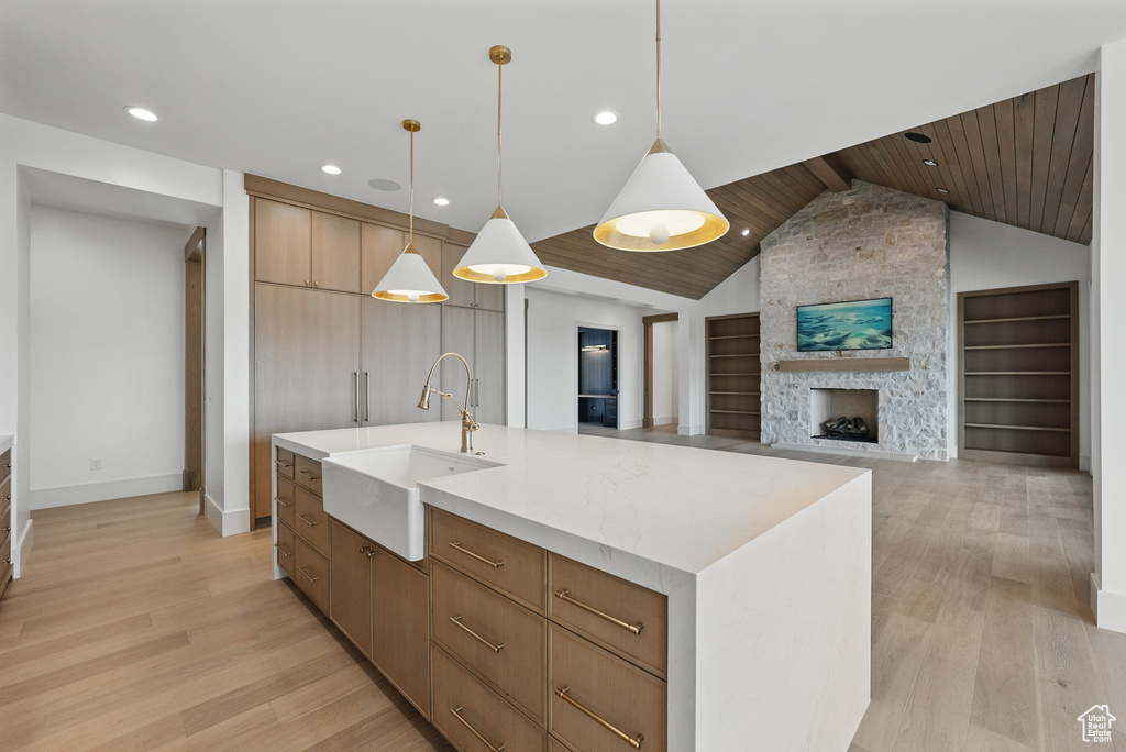 Kitchen with a sink, light wood-style flooring, baseboards, vaulted ceiling, and wood ceiling