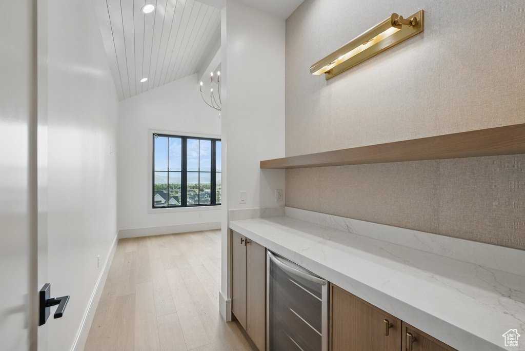 Bar area featuring beverage cooler, light wood-type flooring, recessed lighting, baseboards, and high vaulted ceiling