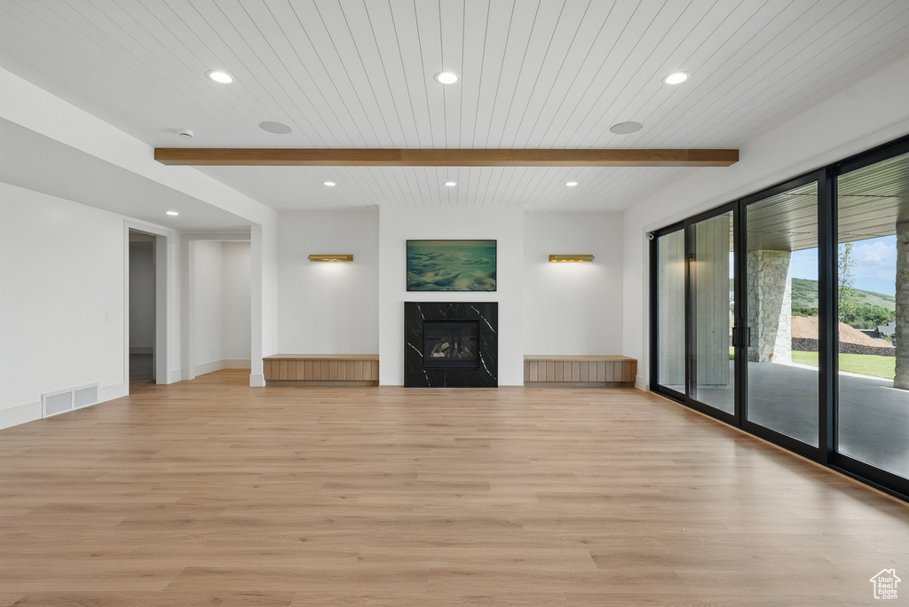 Unfurnished living room featuring light wood-type flooring, beamed ceiling, recessed lighting, and a high end fireplace