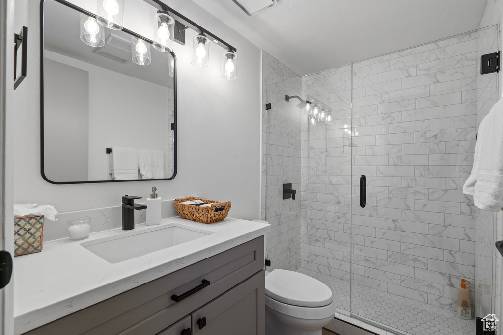 Bathroom with vanity, toilet, and a shower with shower door