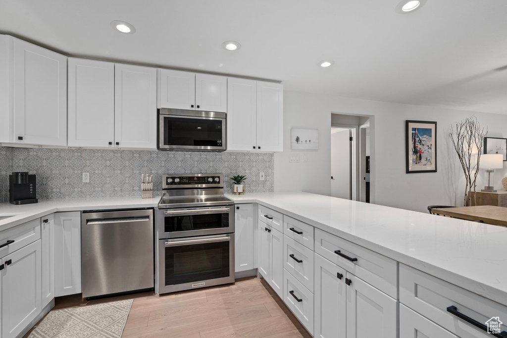 Kitchen featuring white cabinets, appliances with stainless steel finishes, and tasteful backsplash