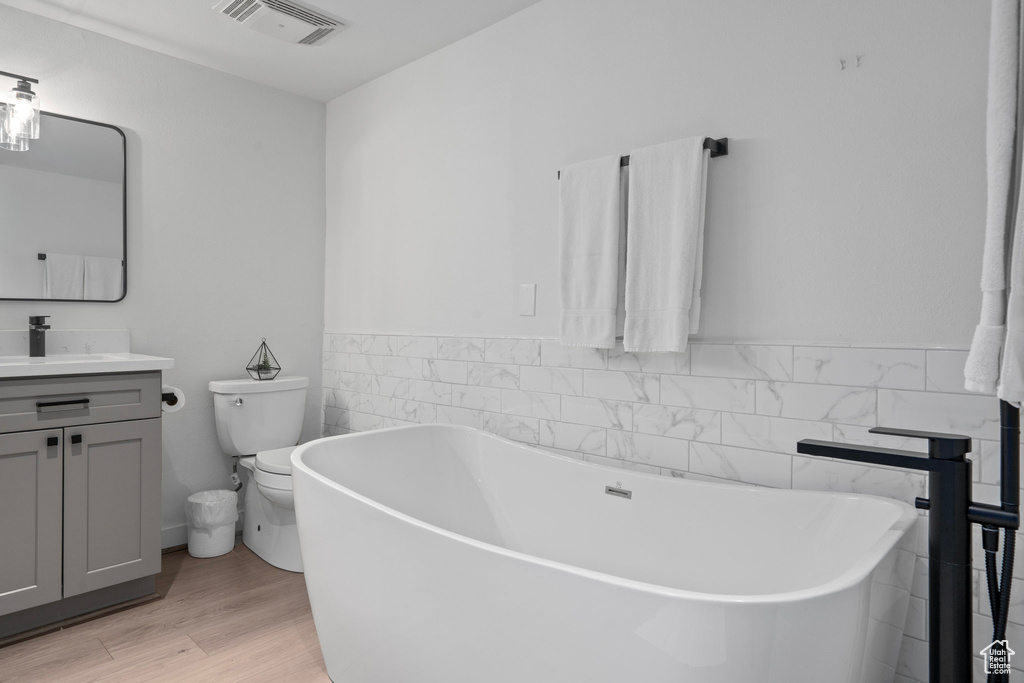 Bathroom featuring vanity, toilet, hardwood / wood-style flooring, and a bathtub