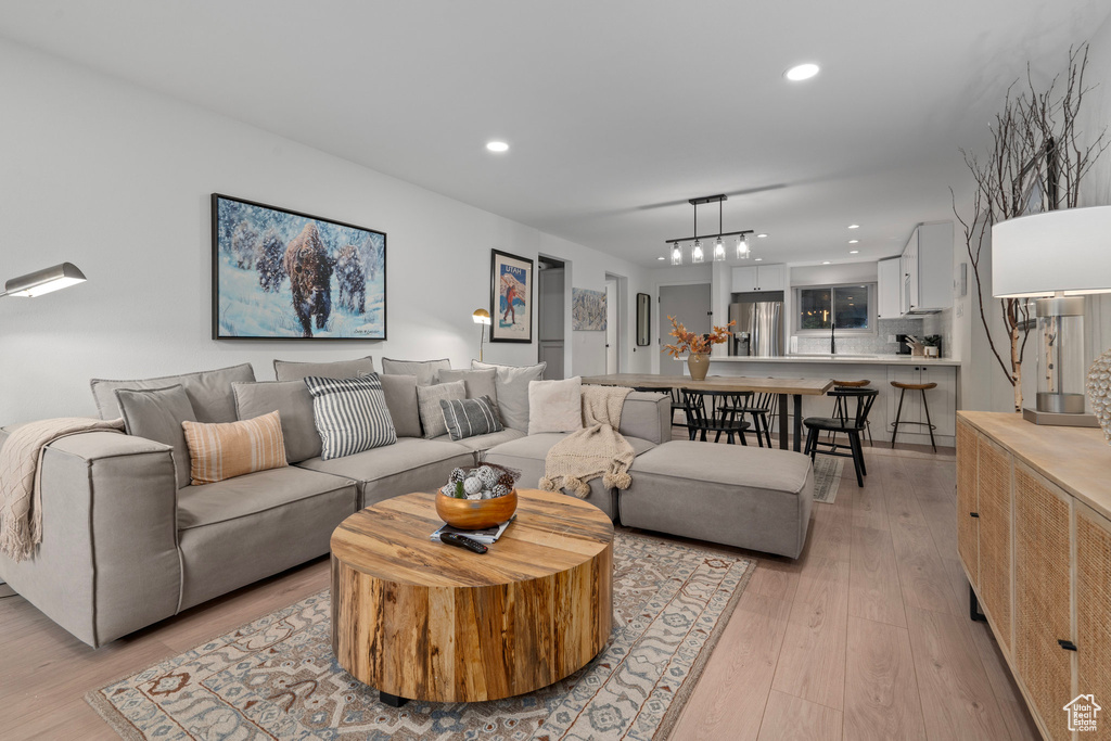 Living room with light wood-type flooring, an inviting chandelier, and sink