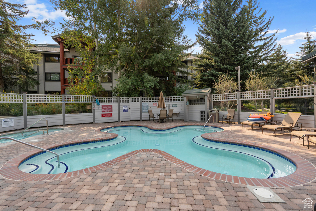 View of swimming pool with a hot tub and a patio area