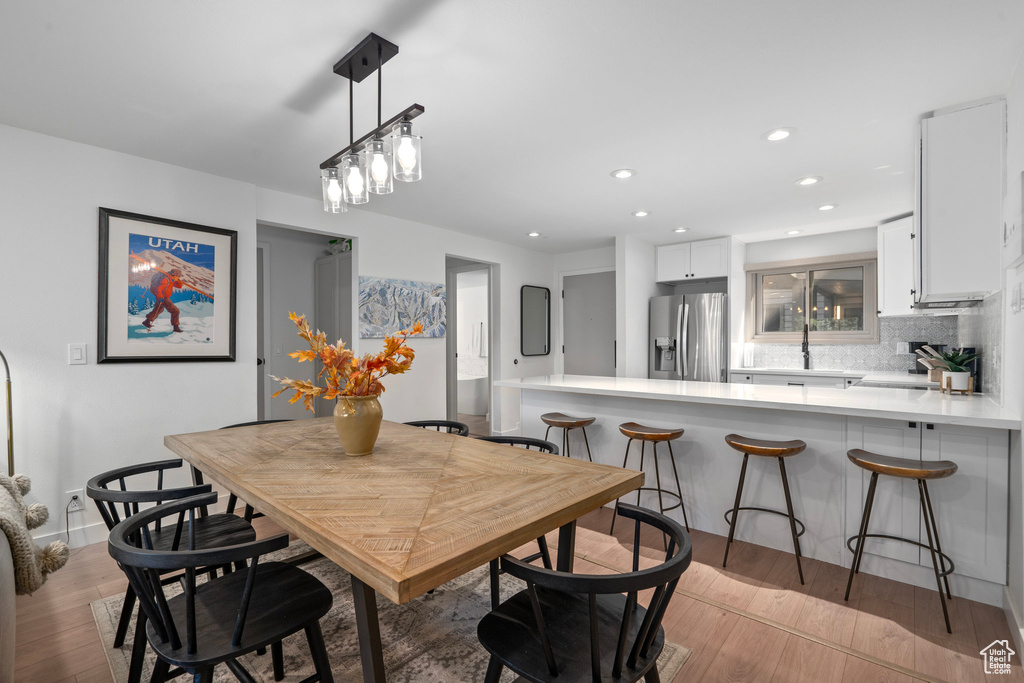 Dining area with light wood-type flooring and a notable chandelier