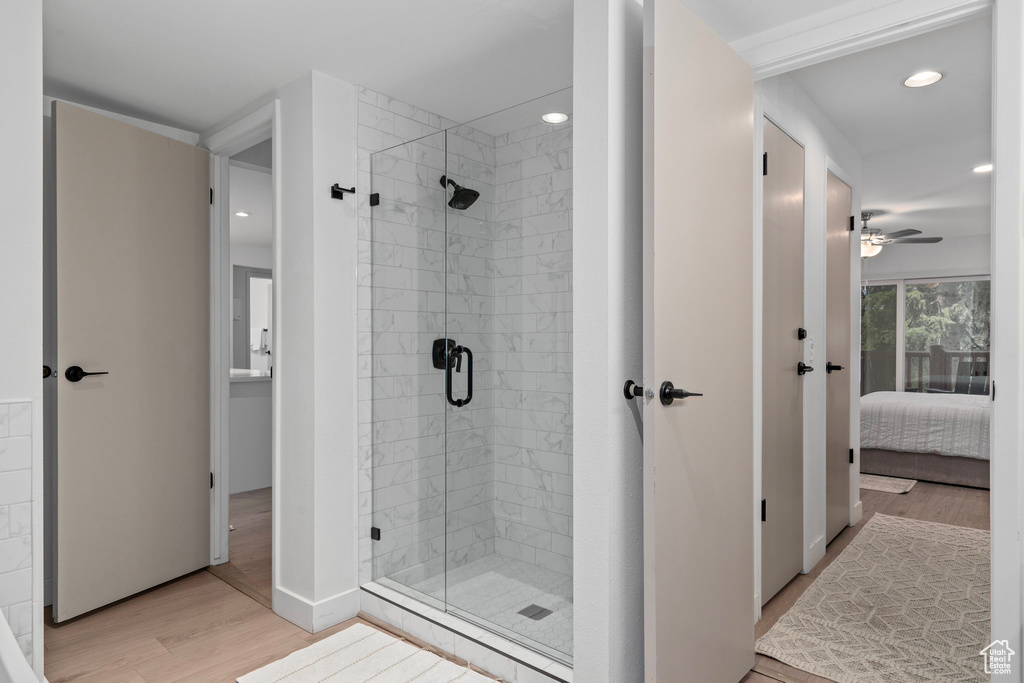 Bathroom with a shower with shower door, ceiling fan, and hardwood / wood-style flooring