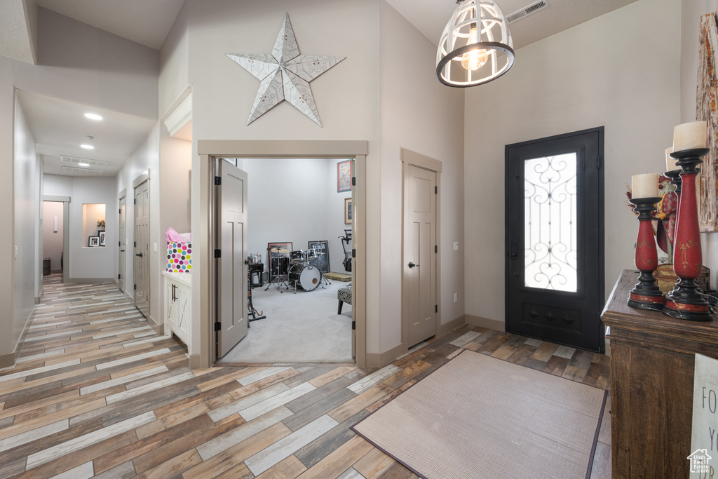 Foyer entrance with a towering ceiling, light hardwood / wood-style flooring, and a notable chandelier