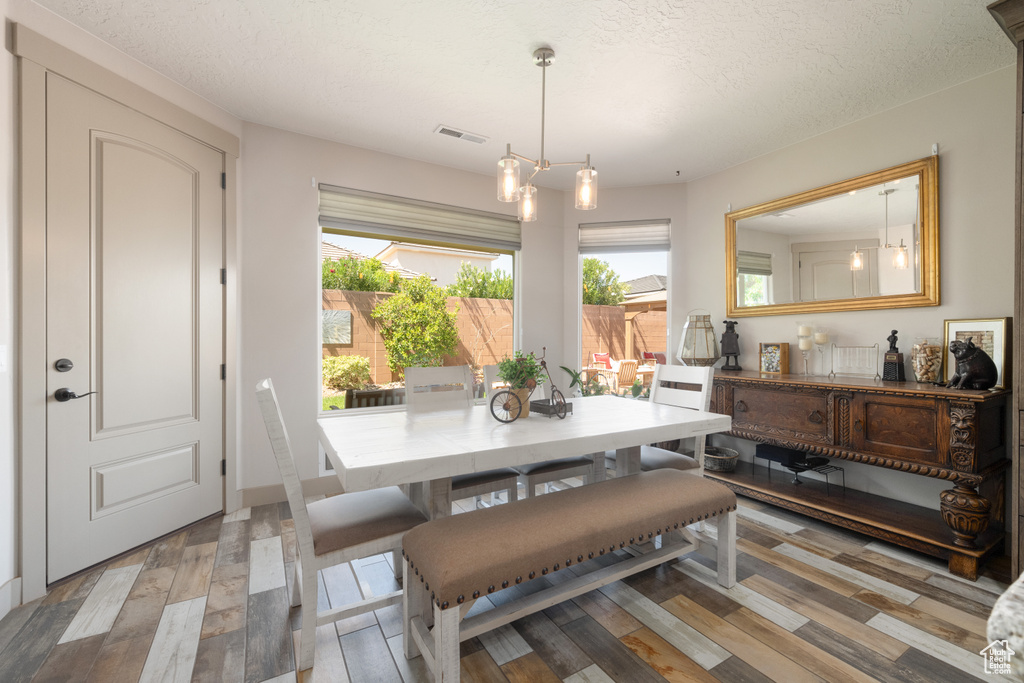 Dining space featuring a textured ceiling, a notable chandelier, and light hardwood / wood-style floors