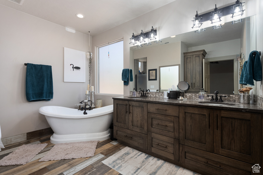 Bathroom featuring a tub to relax in, vanity, and wood-type flooring