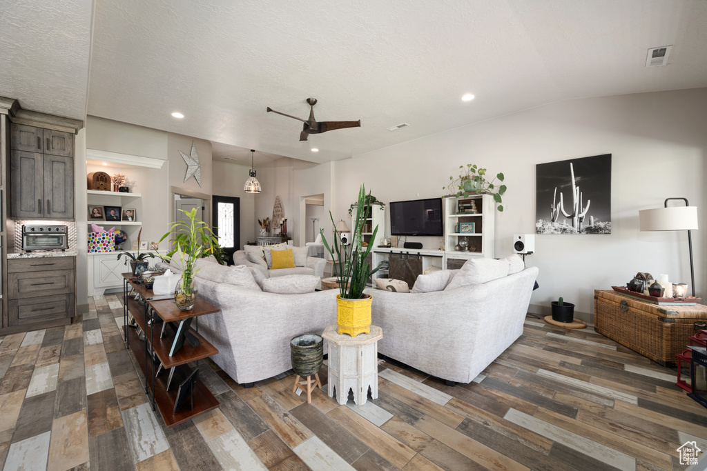 Living room with a textured ceiling, ceiling fan, vaulted ceiling, and dark hardwood / wood-style flooring