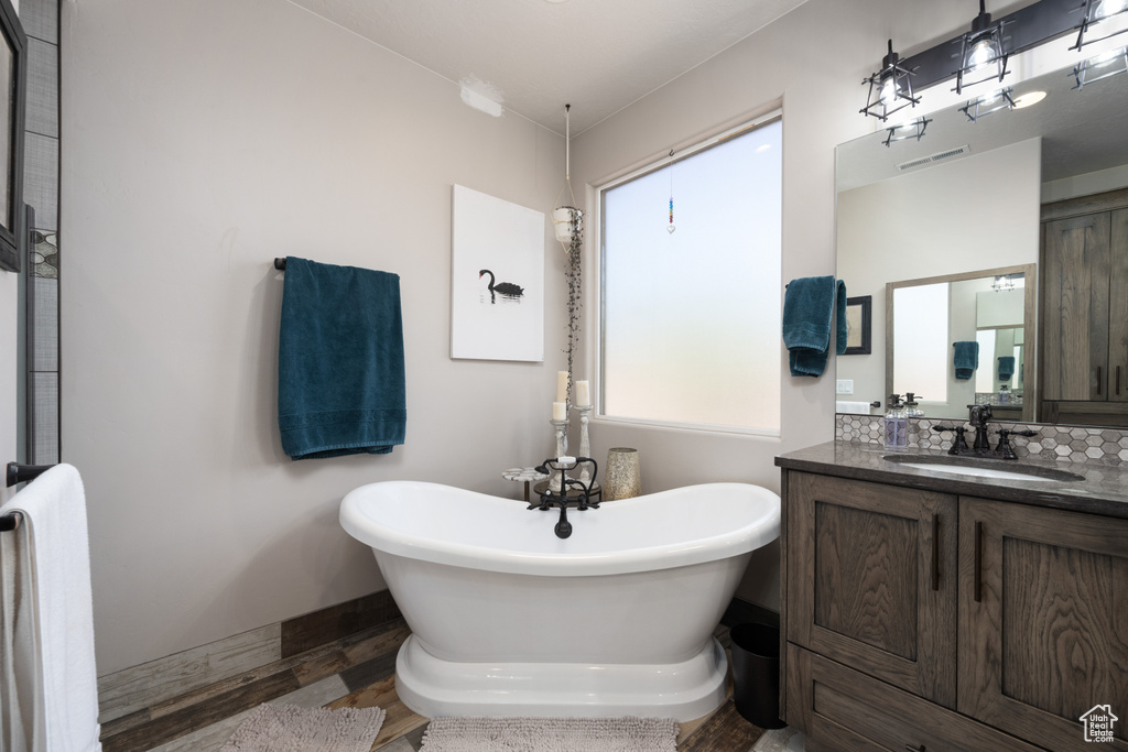 Bathroom with plenty of natural light, a tub, hardwood / wood-style floors, and vanity