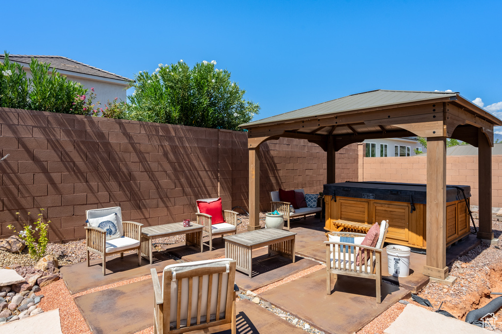 View of patio featuring a hot tub, an outdoor hangout area, and a gazebo