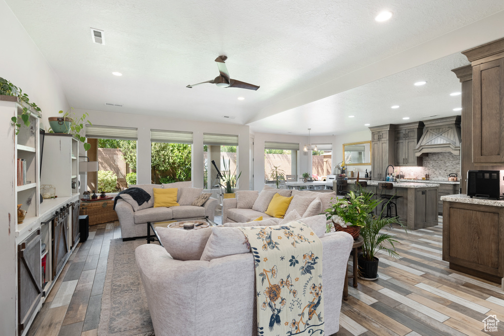 Living room with a wealth of natural light, light hardwood / wood-style flooring, sink, and ceiling fan