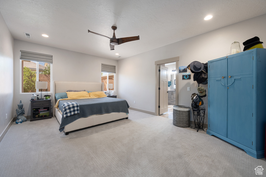 Carpeted bedroom featuring ceiling fan, connected bathroom, and a textured ceiling