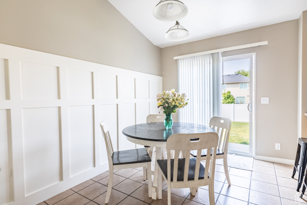 Dining space with lofted ceiling, plenty of natural light, and light tile patterned flooring