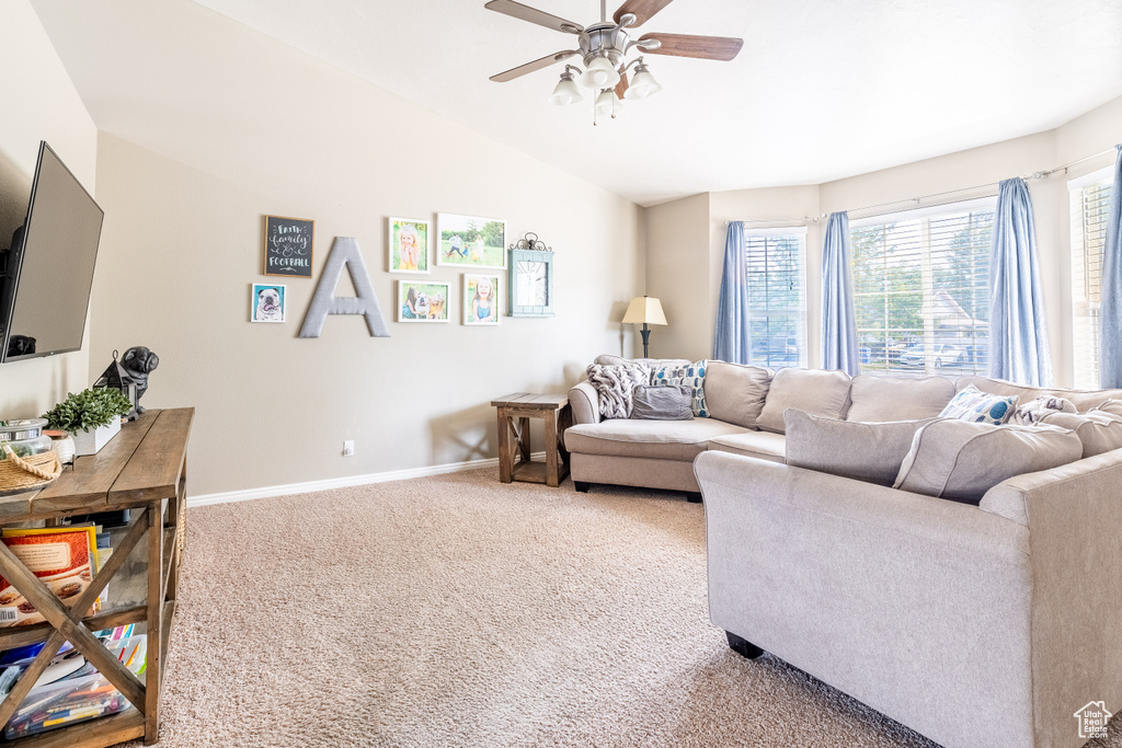 Living room with lofted ceiling, ceiling fan, and carpet flooring