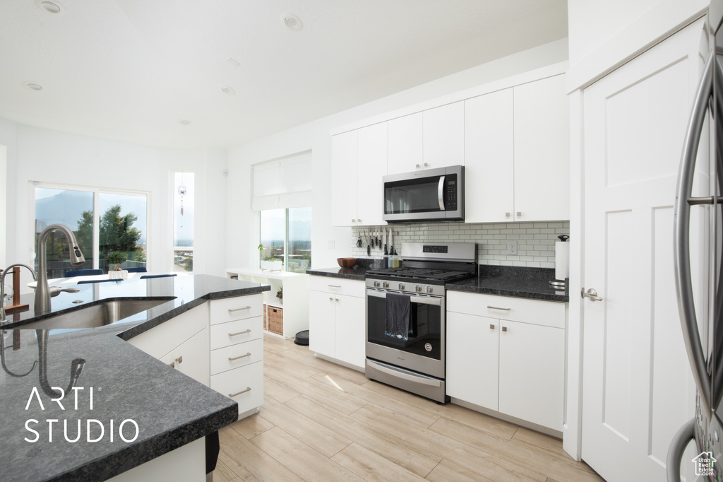 Kitchen with appliances with stainless steel finishes, a wealth of natural light, sink, and white cabinets