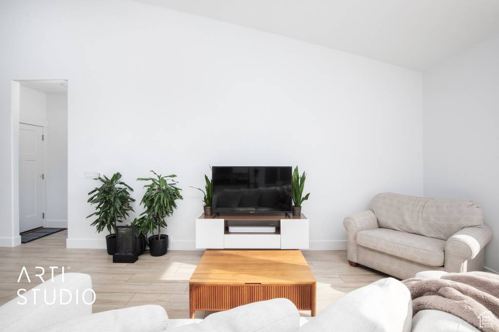 Living room with vaulted ceiling and light hardwood / wood-style flooring