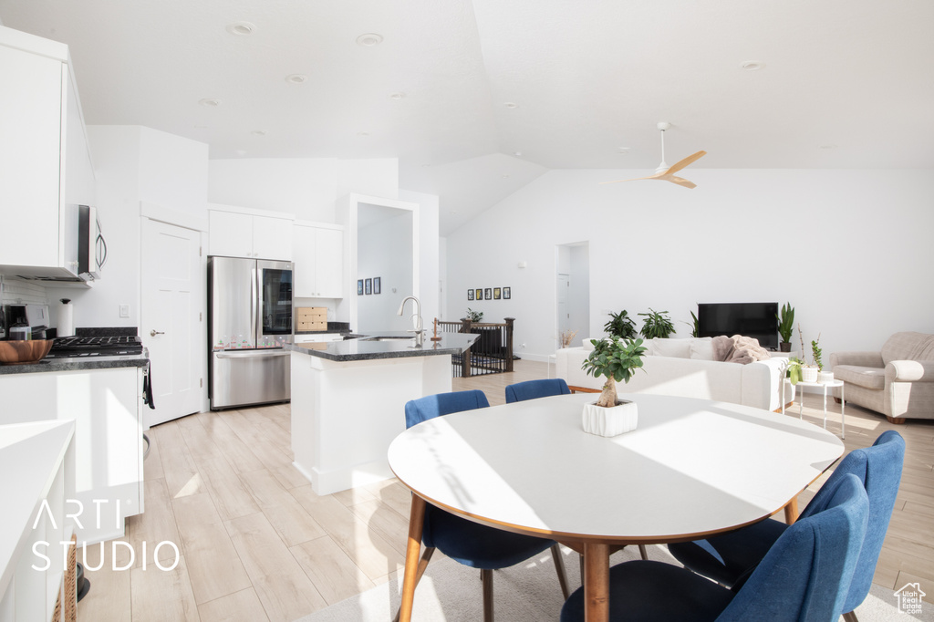 Dining space with high vaulted ceiling, sink, and light wood-type flooring