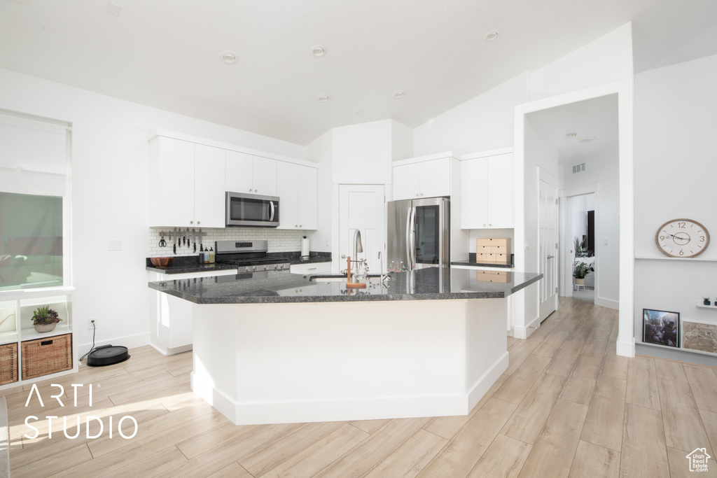 Kitchen featuring an island with sink, stainless steel appliances, sink, and light wood-type flooring