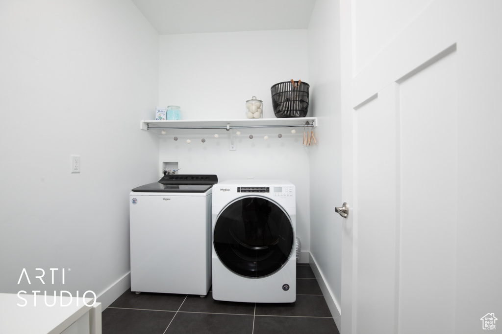 Clothes washing area with dark tile patterned flooring and separate washer and dryer