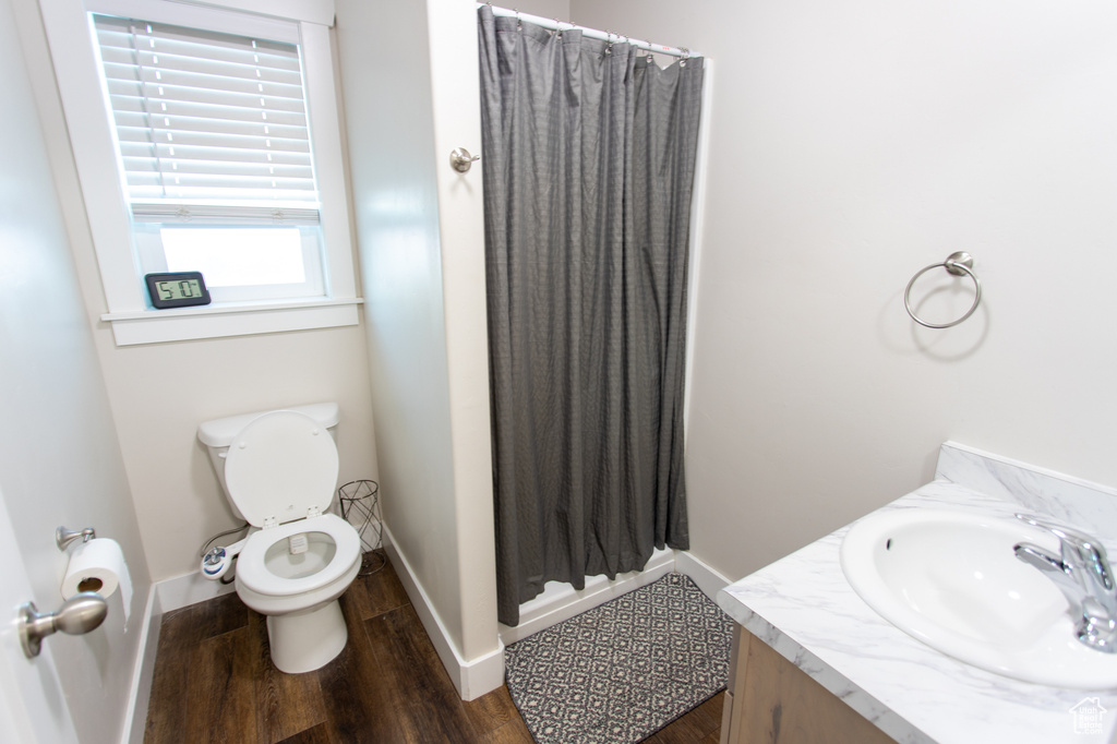 Bathroom featuring curtained shower, hardwood / wood-style floors, toilet, and vanity