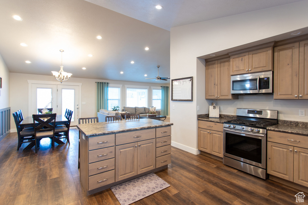 Kitchen featuring ceiling fan with notable chandelier, stainless steel appliances, light brown cabinets, dark wood-type flooring, and a kitchen island