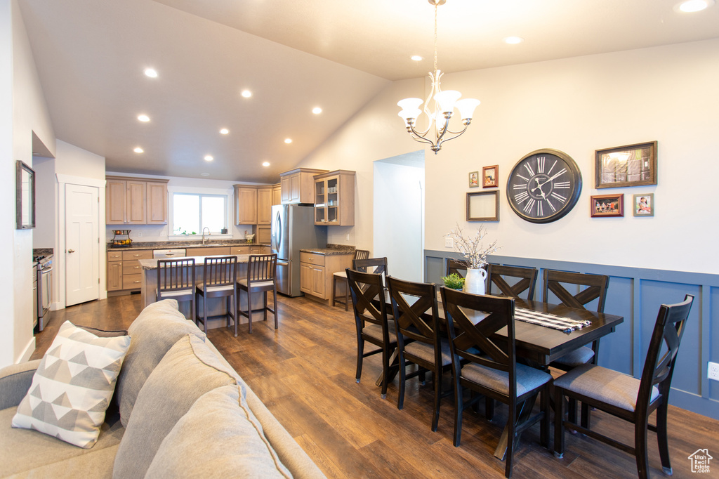 Dining room with dark hardwood / wood-style floors, sink, high vaulted ceiling, and a notable chandelier