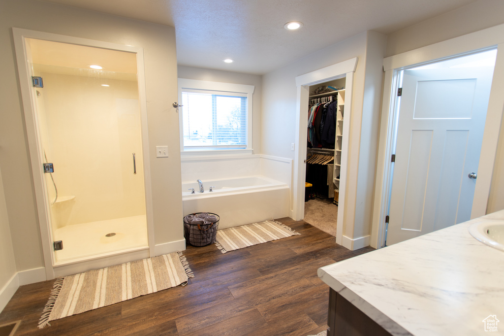 Bathroom featuring hardwood / wood-style floors, separate shower and tub, and vanity