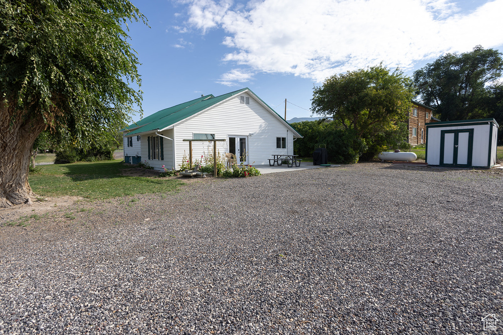 View of home's exterior with a lawn, a shed, and a patio