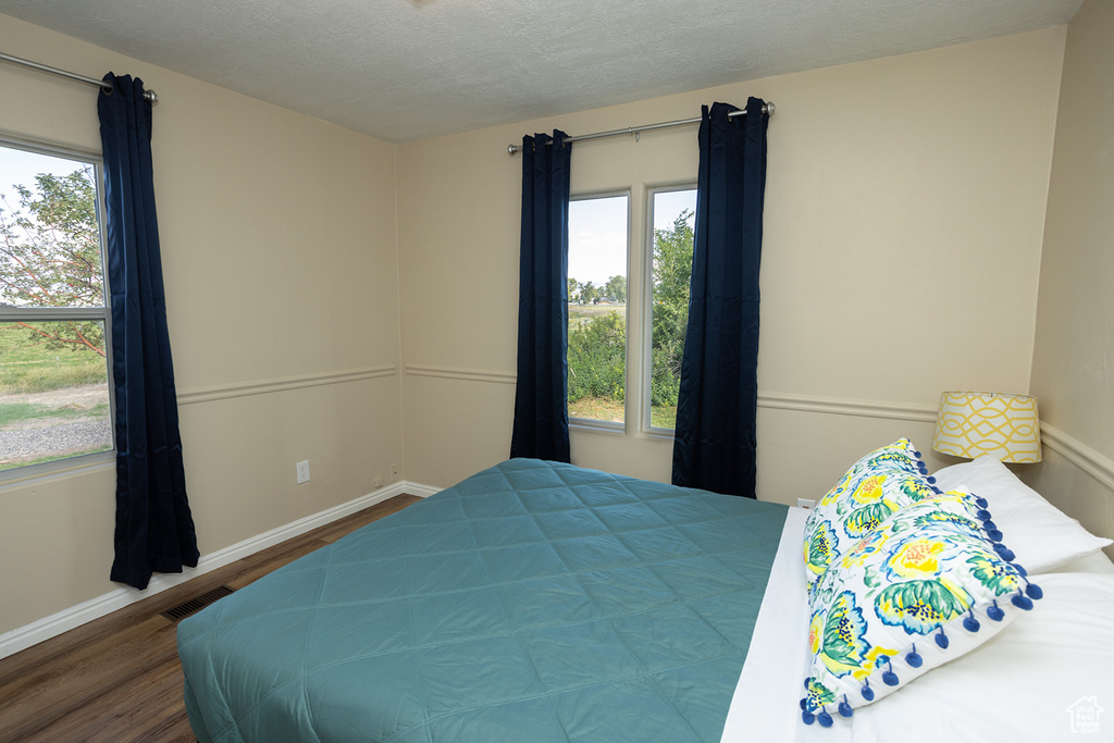 Bedroom with a textured ceiling and hardwood / wood-style floors