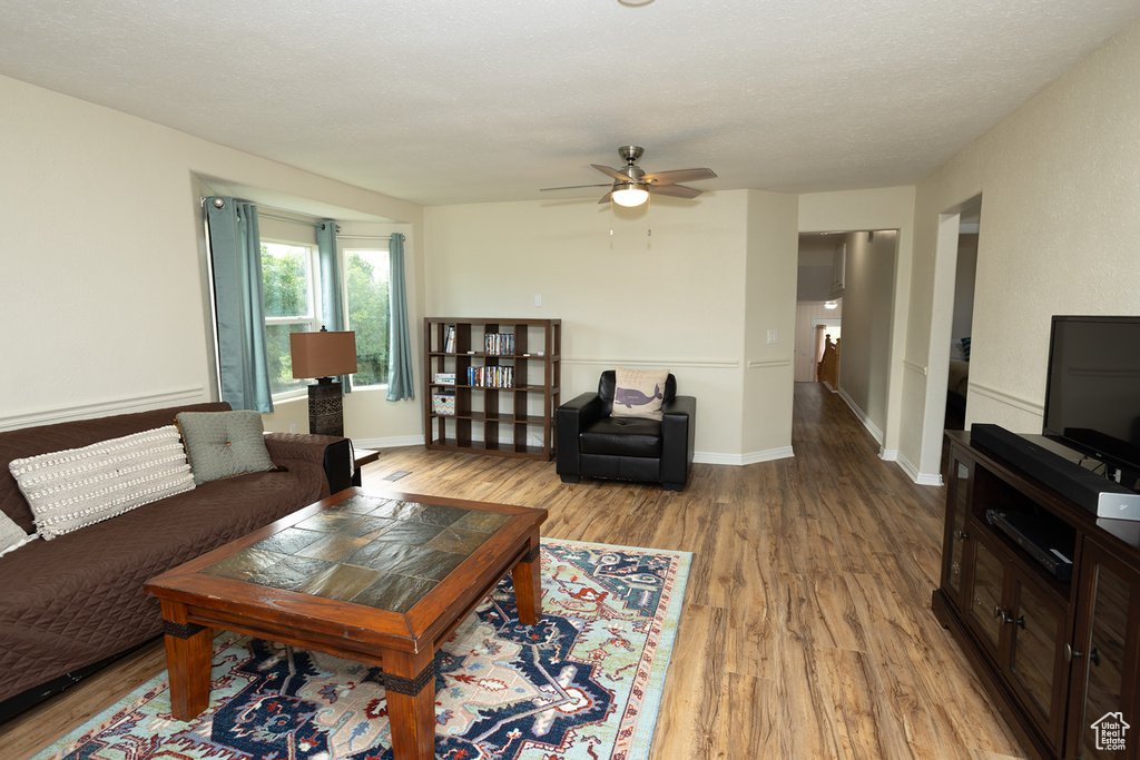 Living room with a textured ceiling, hardwood / wood-style floors, and ceiling fan