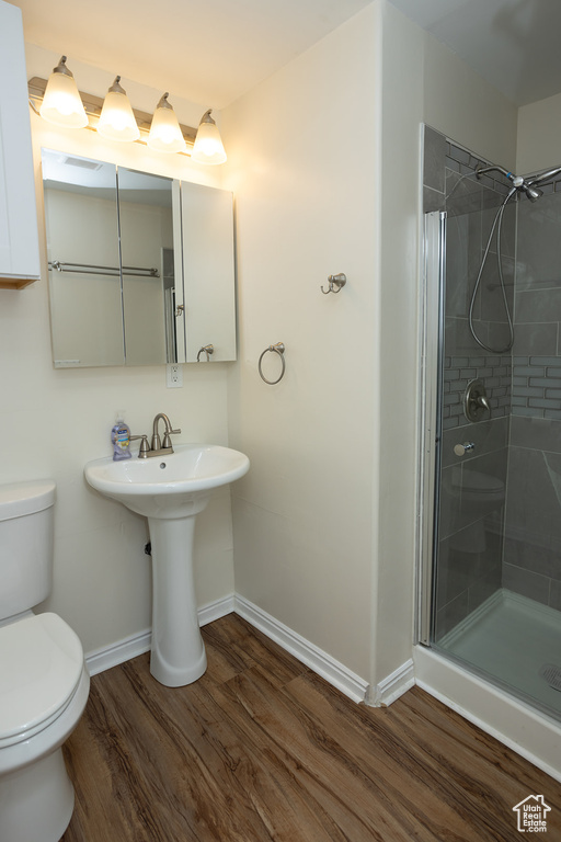 Bathroom featuring a shower with door, toilet, sink, and hardwood / wood-style flooring