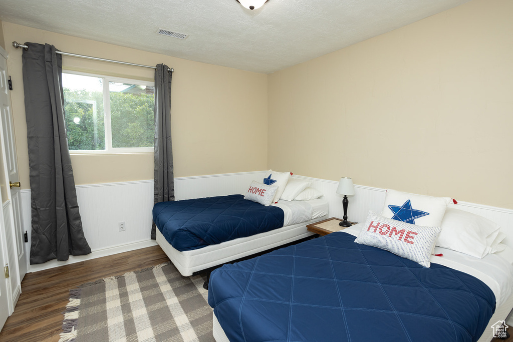 Bedroom with a textured ceiling and dark wood-type flooring