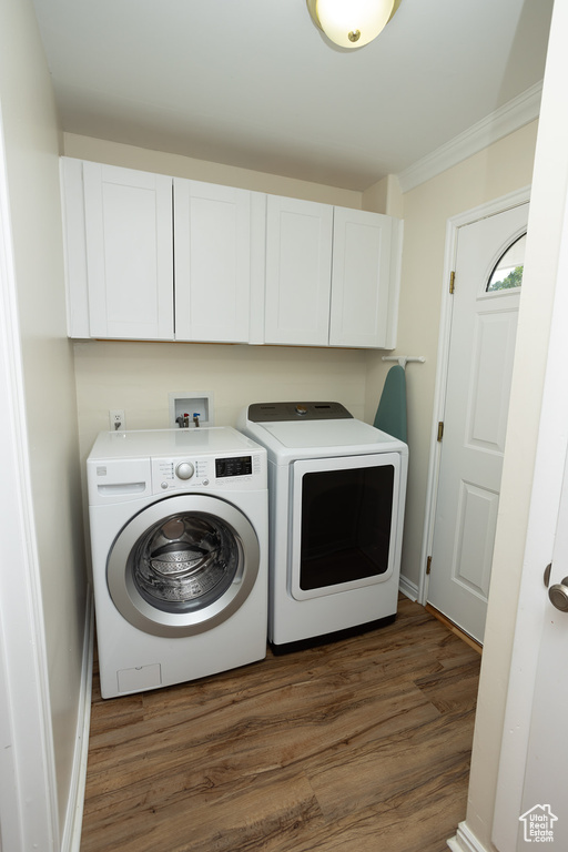 Laundry room featuring crown molding, cabinets, washing machine and clothes dryer, and dark hardwood / wood-style floors