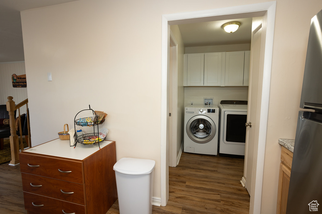 Clothes washing area with dark hardwood / wood-style flooring, cabinets, and independent washer and dryer