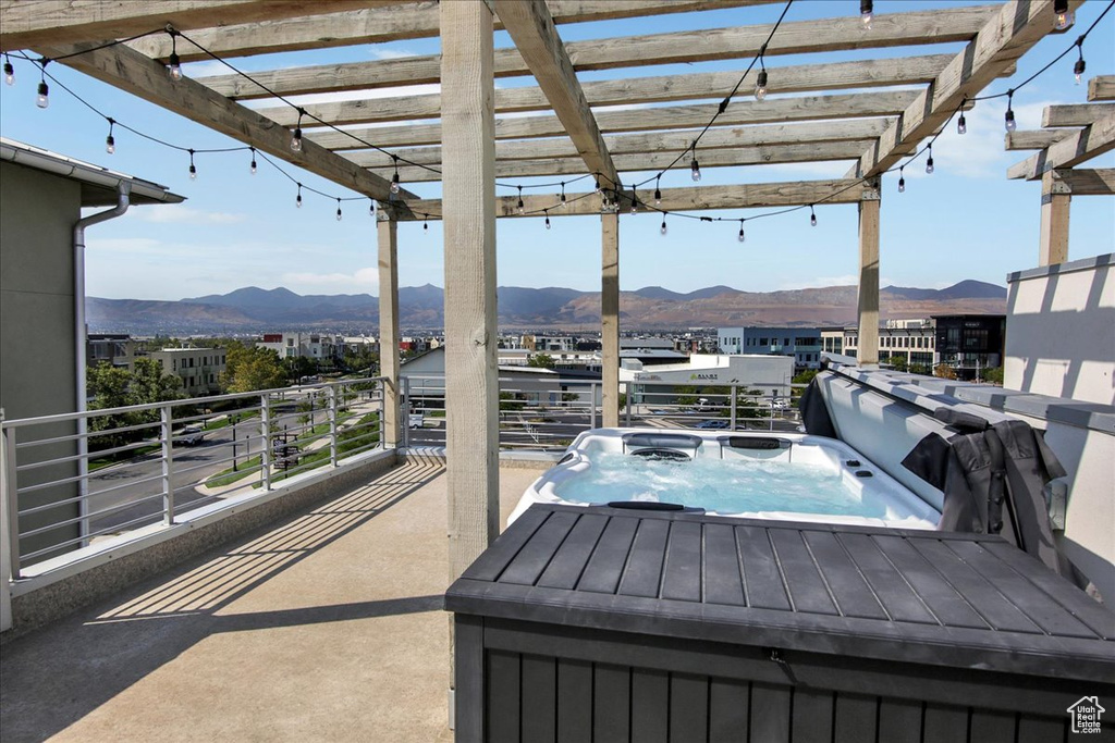 View of patio featuring a mountain view, an outdoor hot tub, a balcony, and a pergola