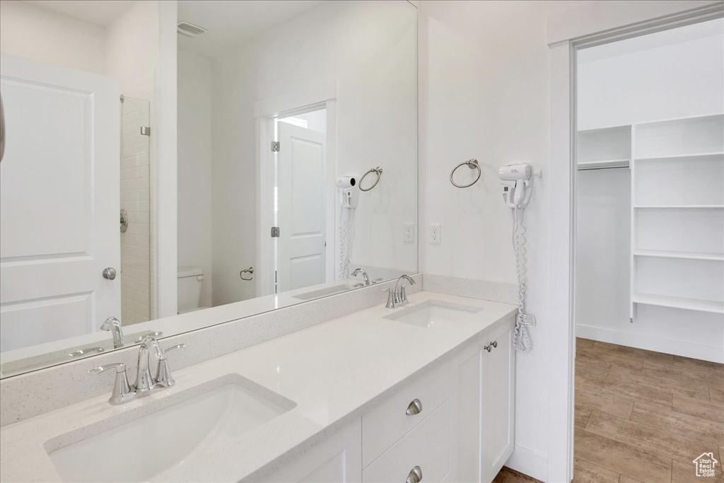 Bathroom featuring hardwood / wood-style floors, walk in shower, toilet, and vanity