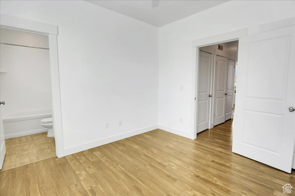 Unfurnished bedroom with ceiling fan, connected bathroom, and light hardwood / wood-style floors