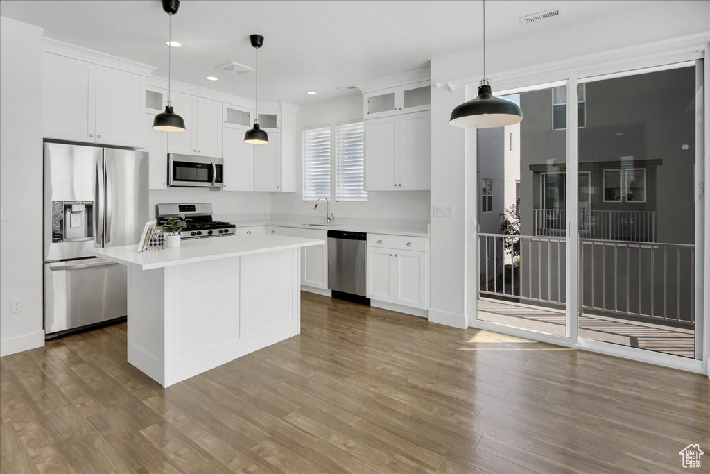 Kitchen featuring pendant lighting, hardwood / wood-style floors, a kitchen island, and stainless steel appliances