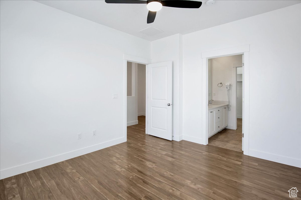 Unfurnished bedroom featuring dark wood-type flooring, connected bathroom, and ceiling fan