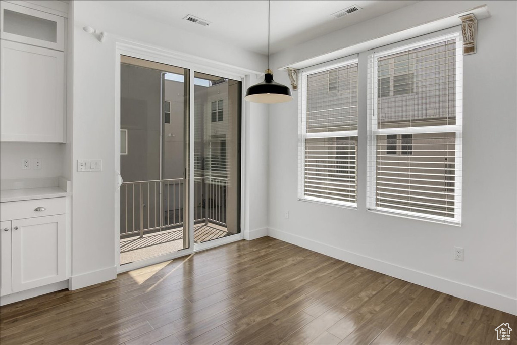 Unfurnished dining area featuring dark wood-type flooring and plenty of natural light