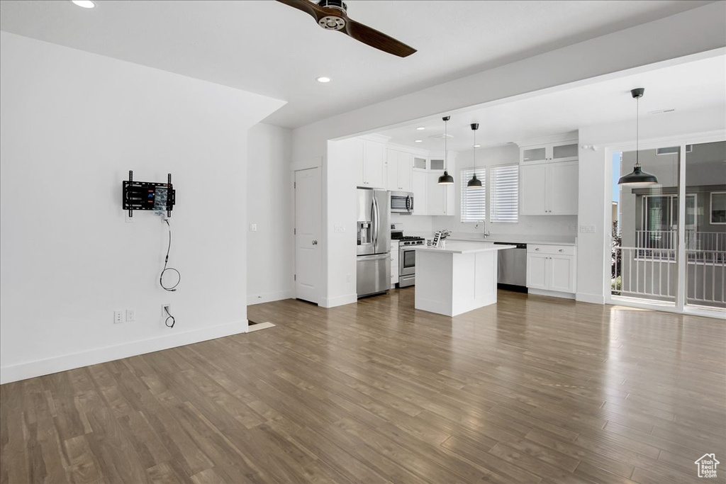 Unfurnished living room featuring ceiling fan and hardwood / wood-style flooring