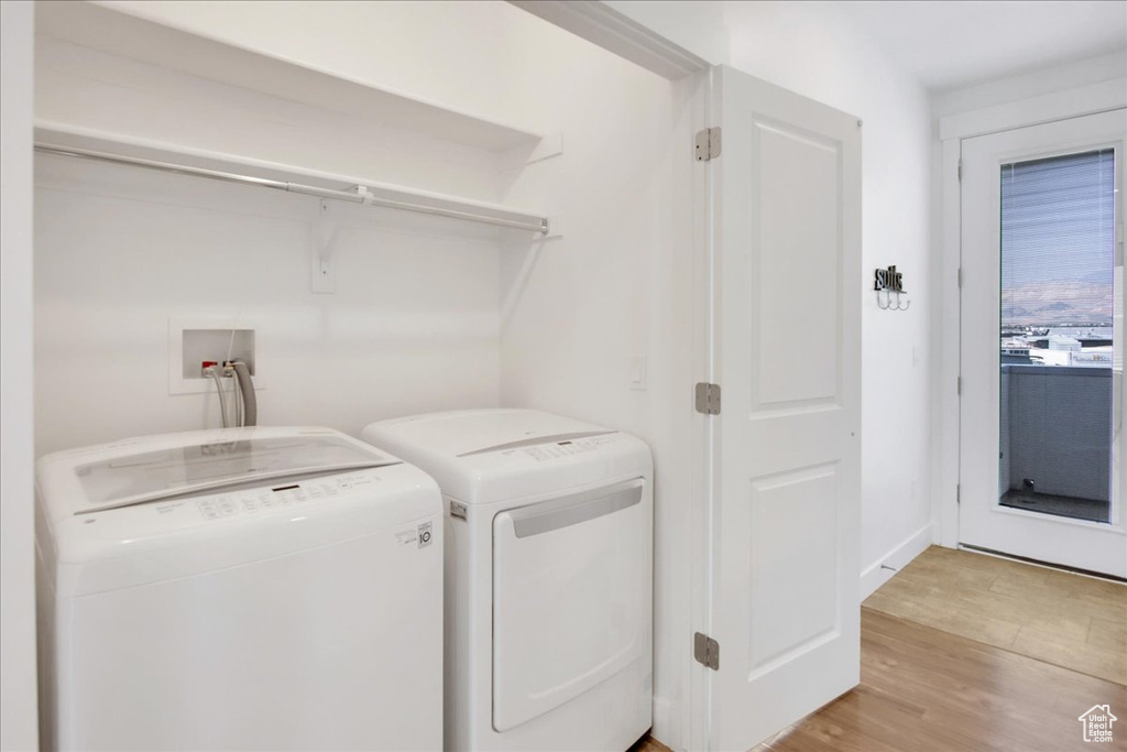 Washroom with independent washer and dryer and light hardwood / wood-style floors